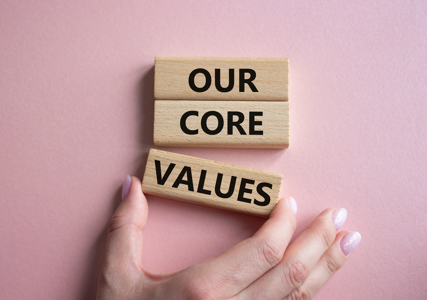 Our core values symbol. Concept words Our core values on wooden blocks. Beautiful pink background. Businessman hand. Business and Our core values concept. Copy space.